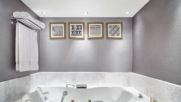 A modern bathroom with a large bathtub, a towel rack, and four framed wall art pieces.