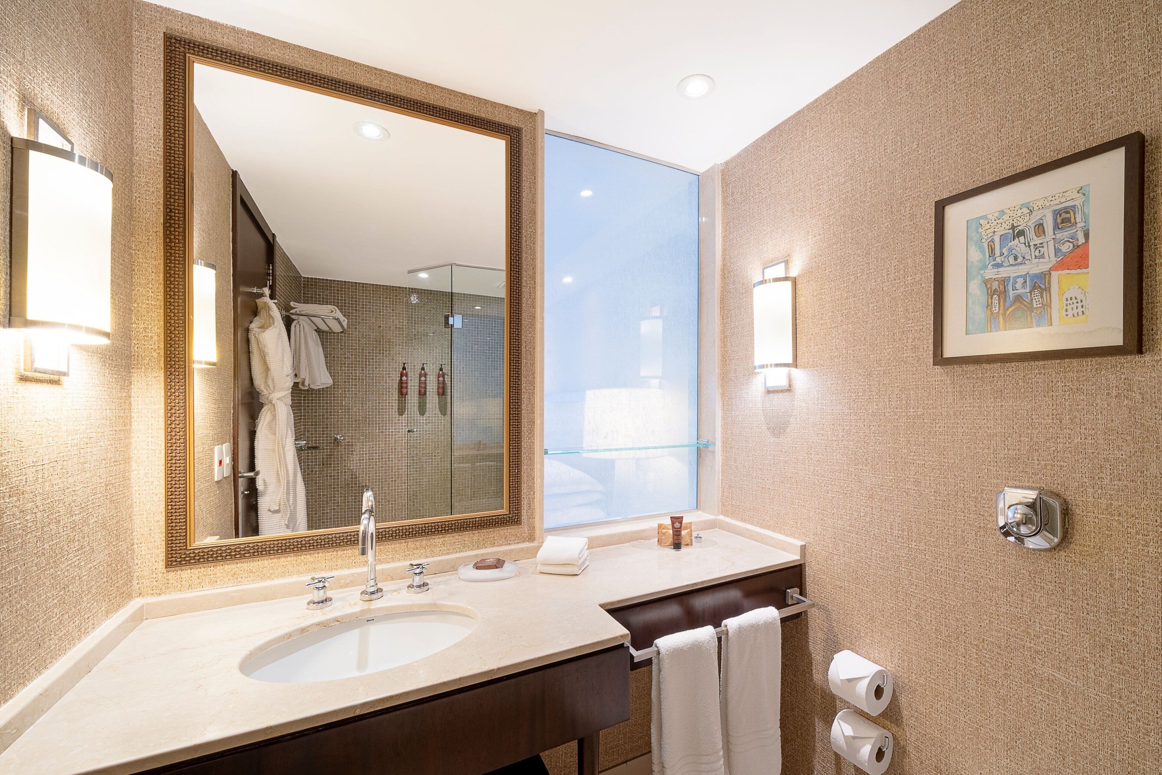 A modern bathroom with a large mirror, a sink, and a glass shower enclosure.