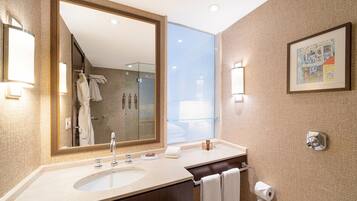 A modern bathroom with a large mirror, a sink, and a glass shower enclosure.