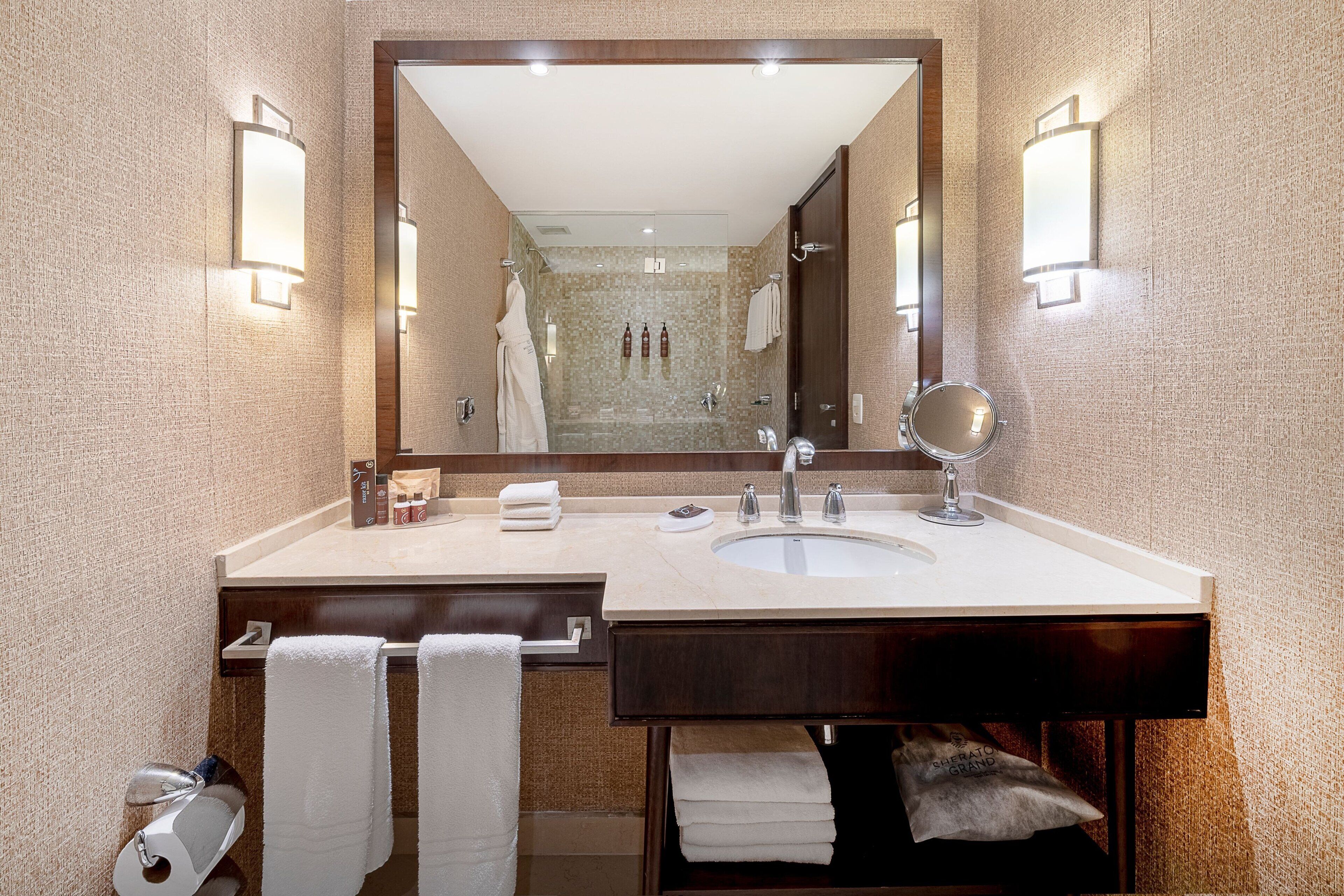 A bathroom with a double sink, a large mirror, and two wall-mounted lights.