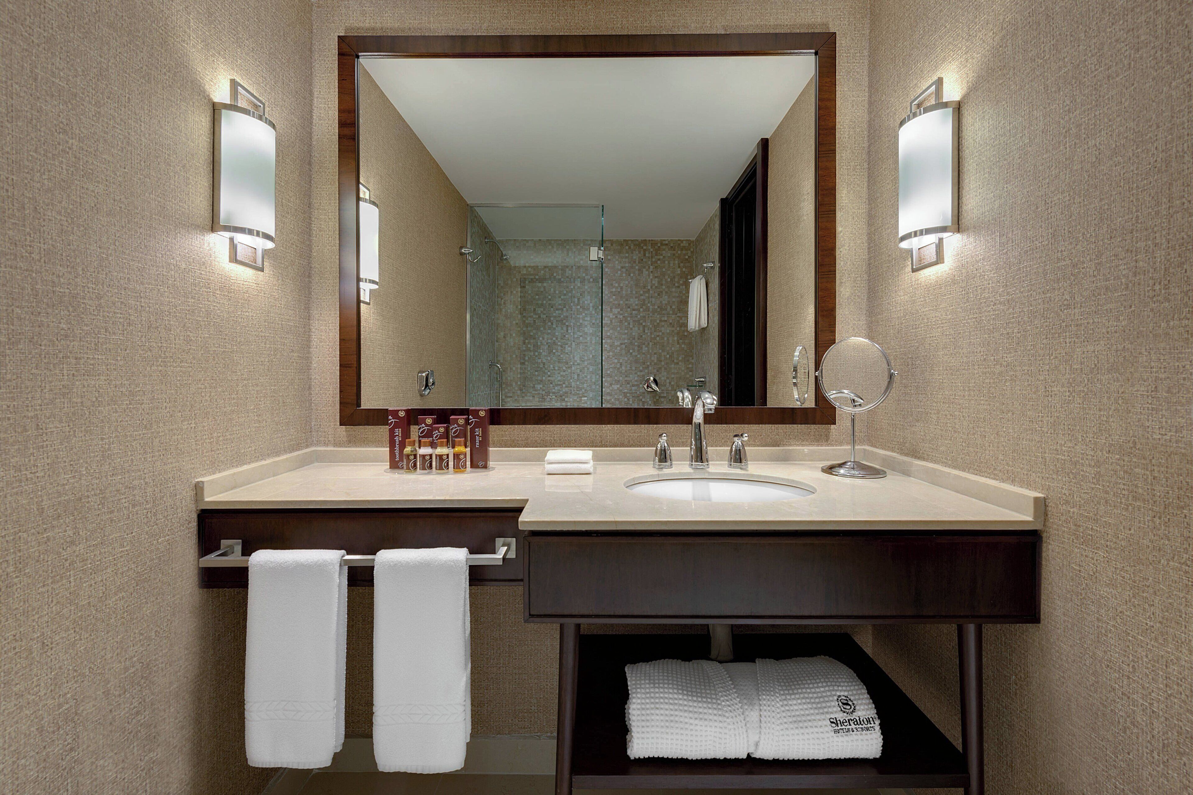 Un baño moderno con un espejo grande, dos lavamanos y un perchero para toallas.