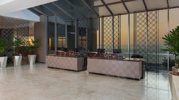 A modern lobby with marble flooring, a reception desk, and a glass partition with a geometric pattern.