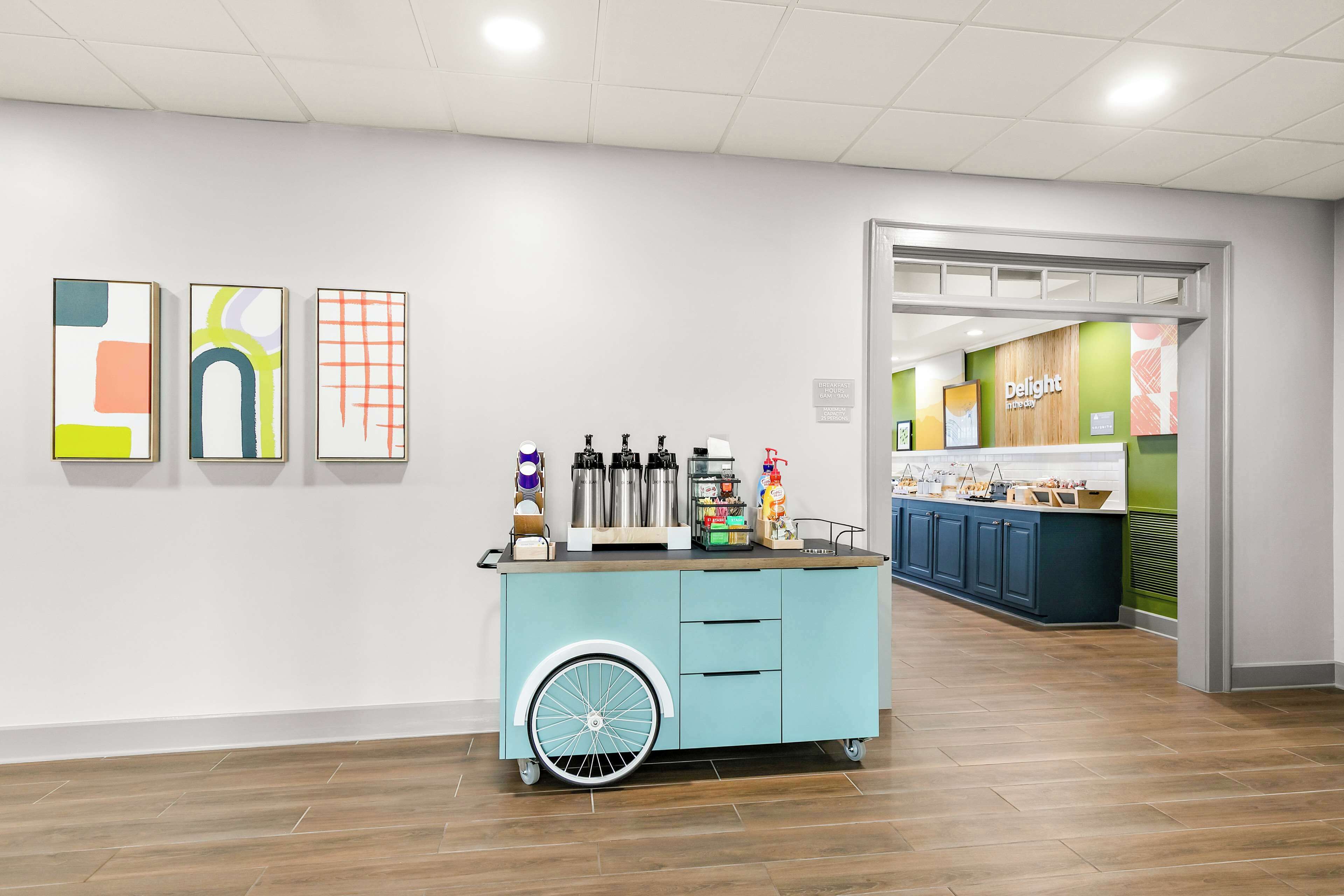 A clean, modern interior with a light blue cart, a coffee station, and a counter labeled "Delight."