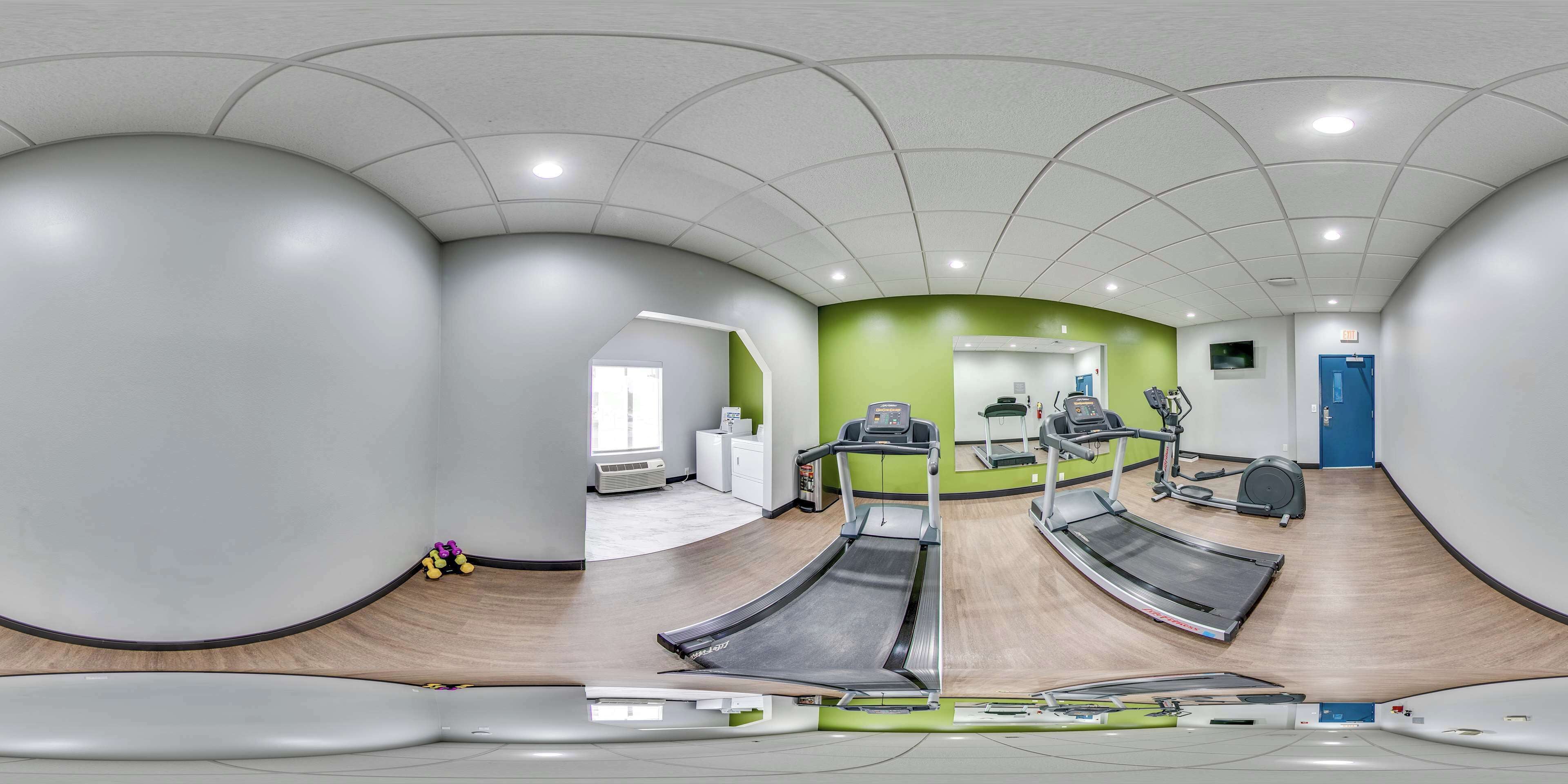 A gym with treadmills, a mirror, and a blue door.