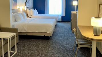 Habitación de hotel con cama, escritorio, silla y lámpara.