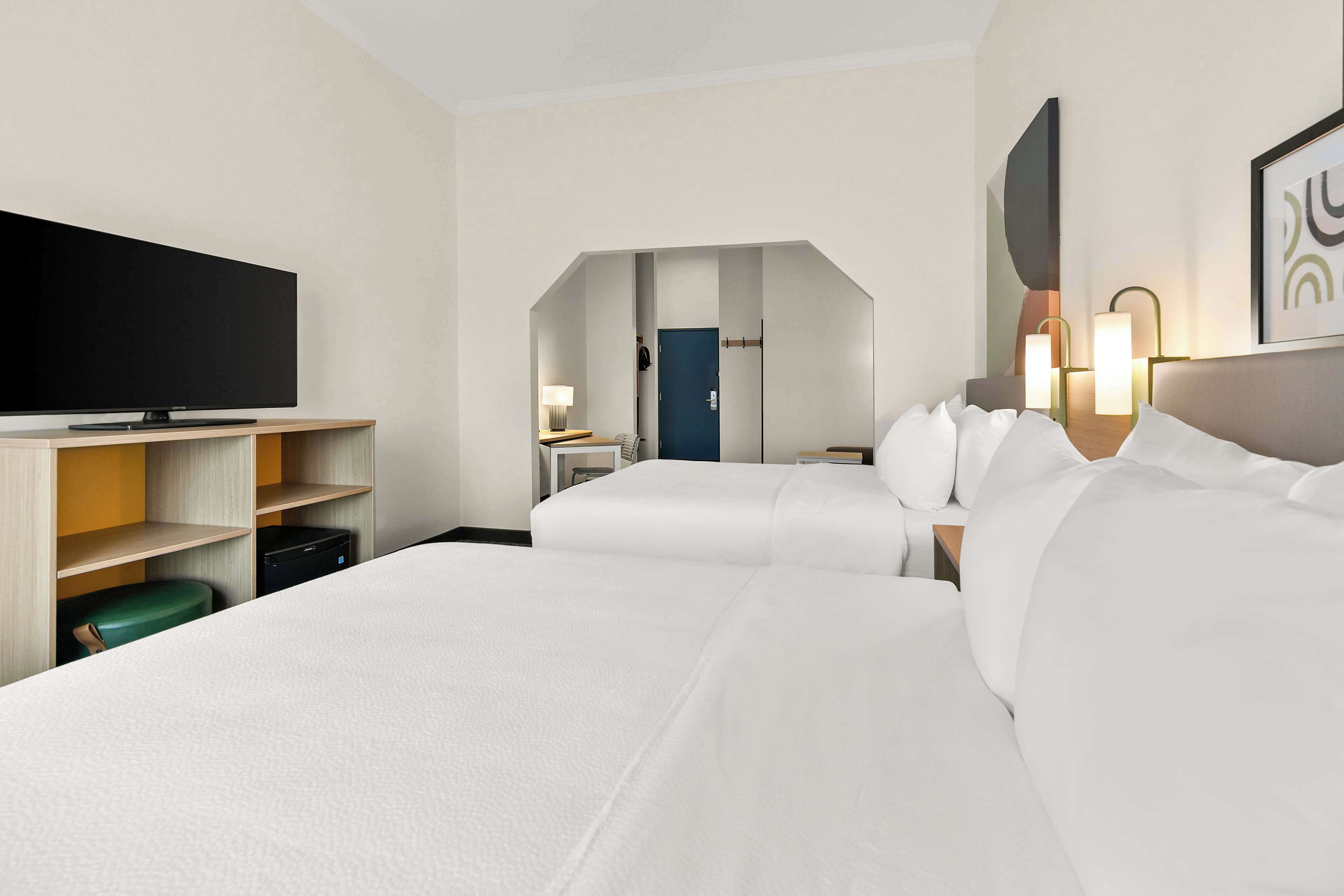 A hotel room with two beds, a flat-screen TV, a desk, and a chair.
