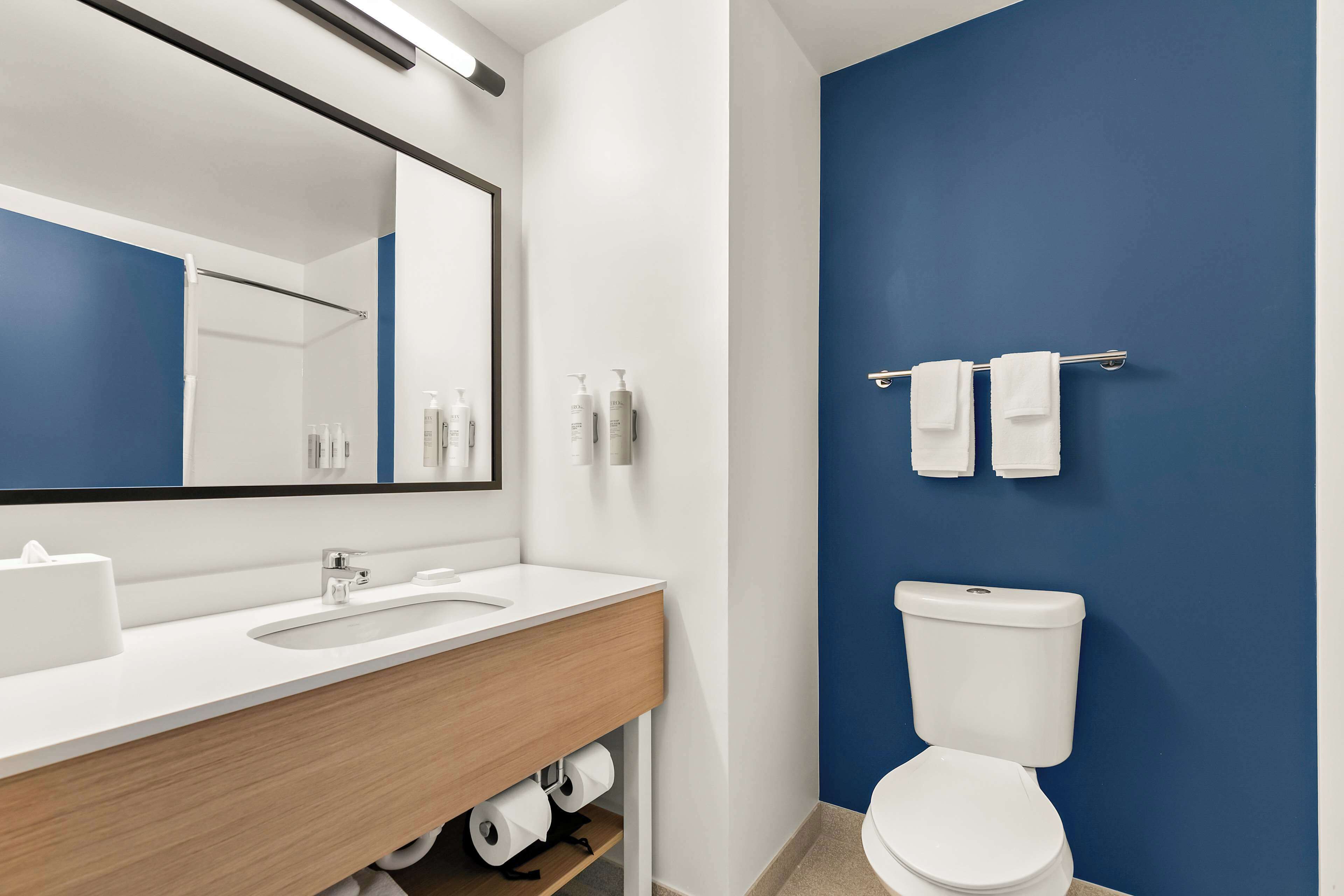 A modern bathroom with a white sink, mirror, and toilet.