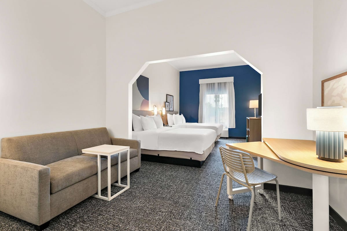 A hotel room with a sofa, a small table, a desk, and a bed.