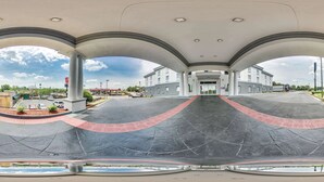 A spacious indoor area with a curved floor, large columns, and a view of a building in the background. - Spark by Hilton Commerce, GA (Commerce)