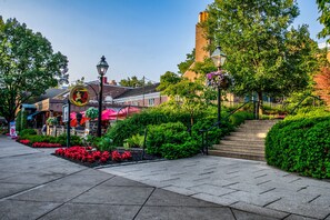 A paved pathway with a sign, lush greenery, and a building with a chimney.