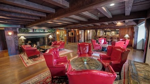 A spacious room with wooden beams, red leather chairs, a fireplace, and a bar area. - Nassau Inn (Princeton)