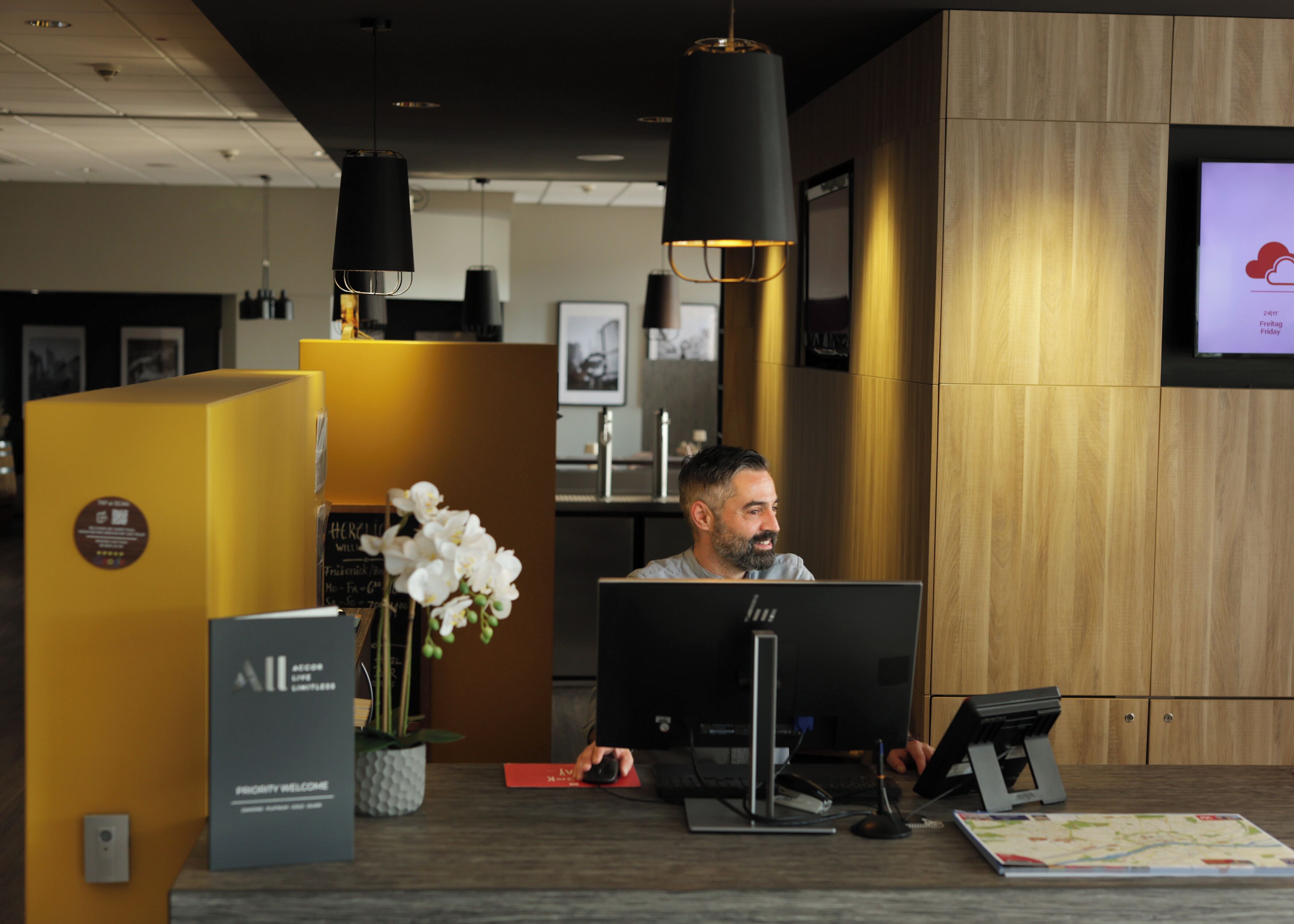 A reception desk with a computer, a plant, and a welcome sign.