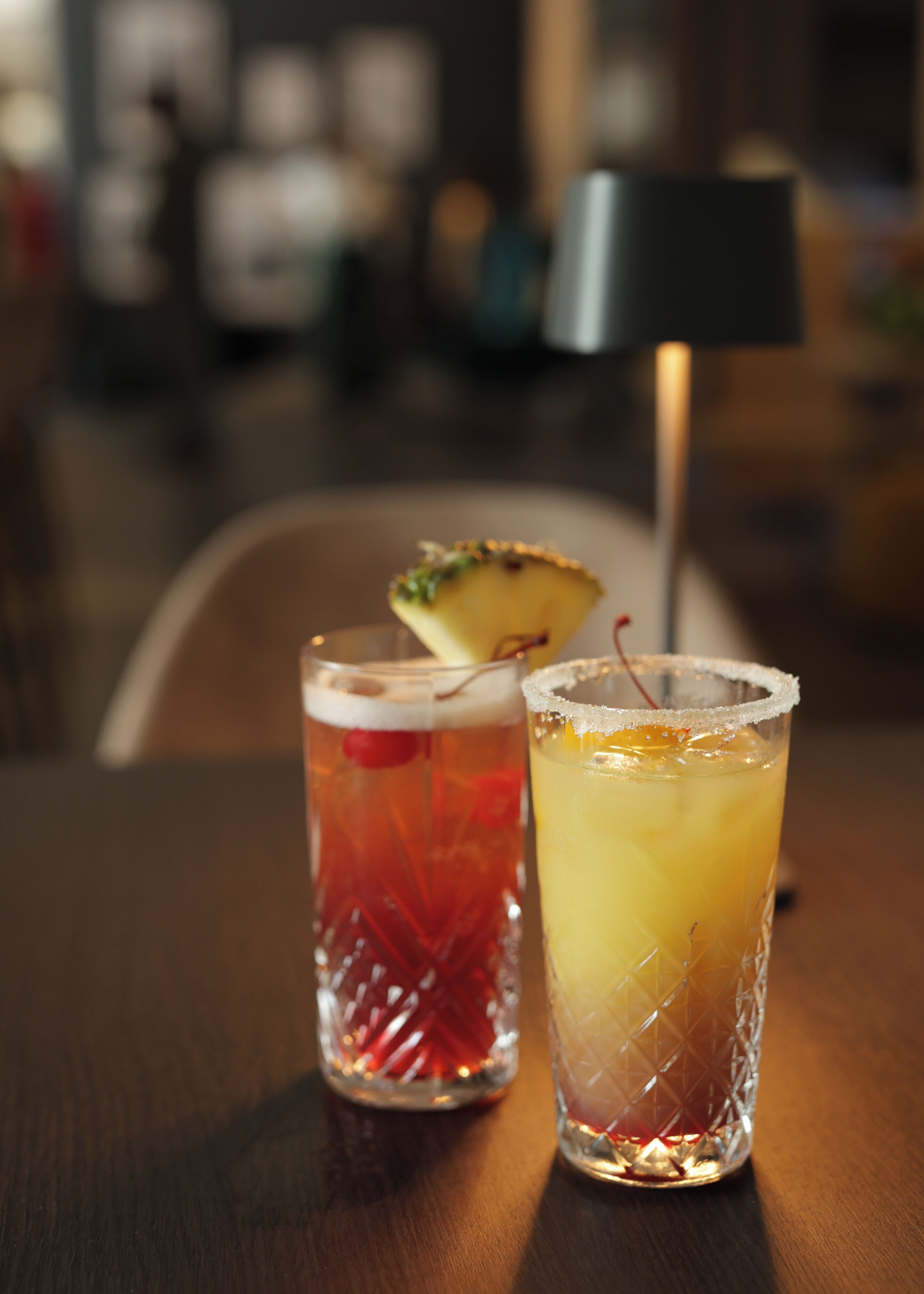 Deux verres de cocktails sur une table en bois, avec un arrière-plan flou.