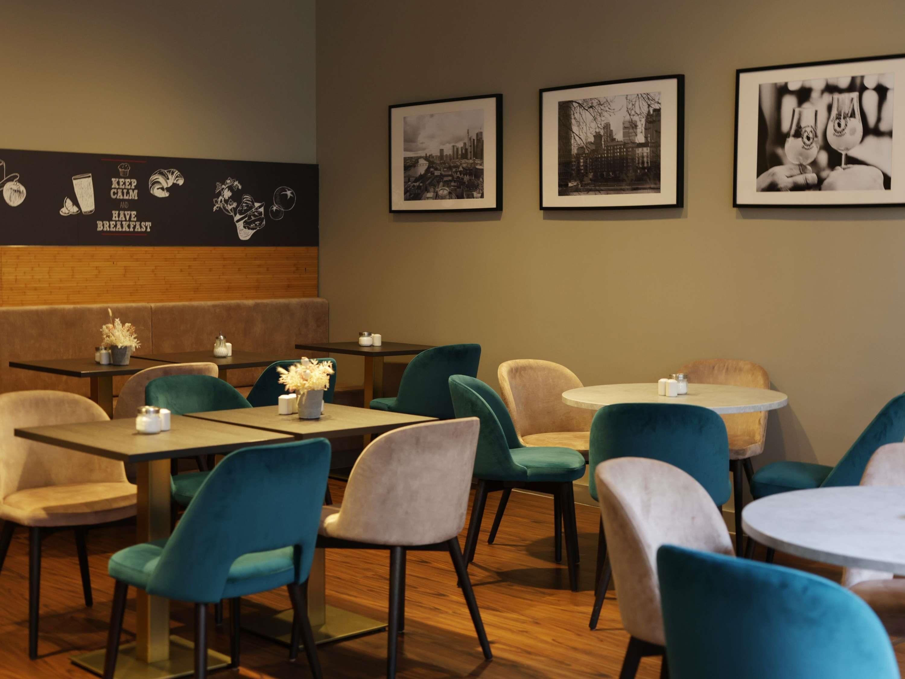 A restaurant interior with booths and tables, framed pictures on the wall, and a menu board with food items.