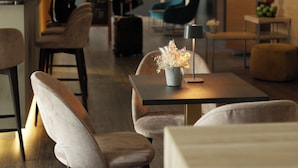 Un hall d’hôtel moderne avec un bar, des espaces aménagés pour s’asseoir et une personne à l’arrière-plan.