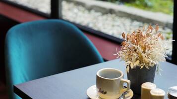 A table with a cup and saucer, a small potted plant, and salt shakers.