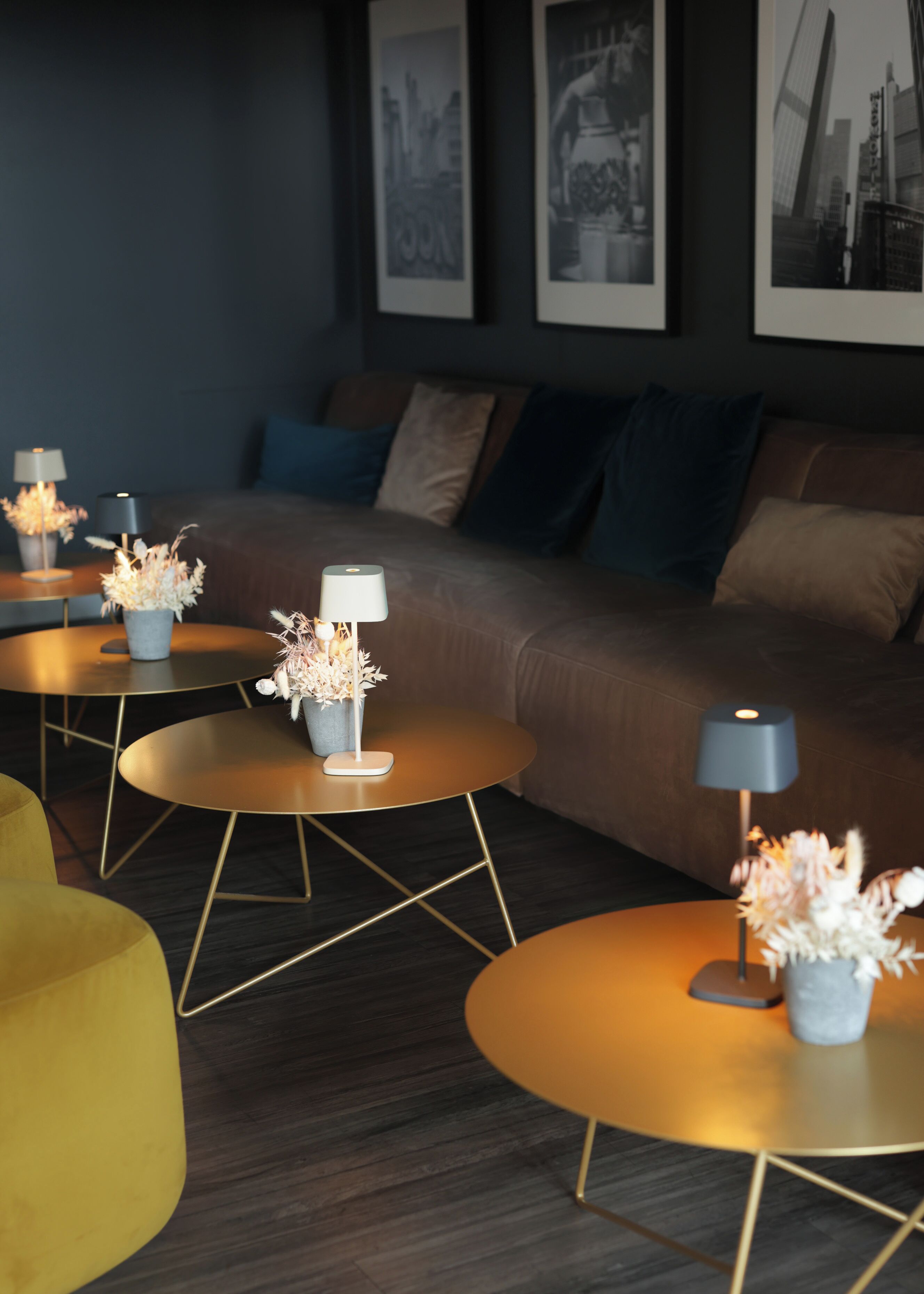 A modern living room with a sofa, round tables with lamps, and decorative vases.