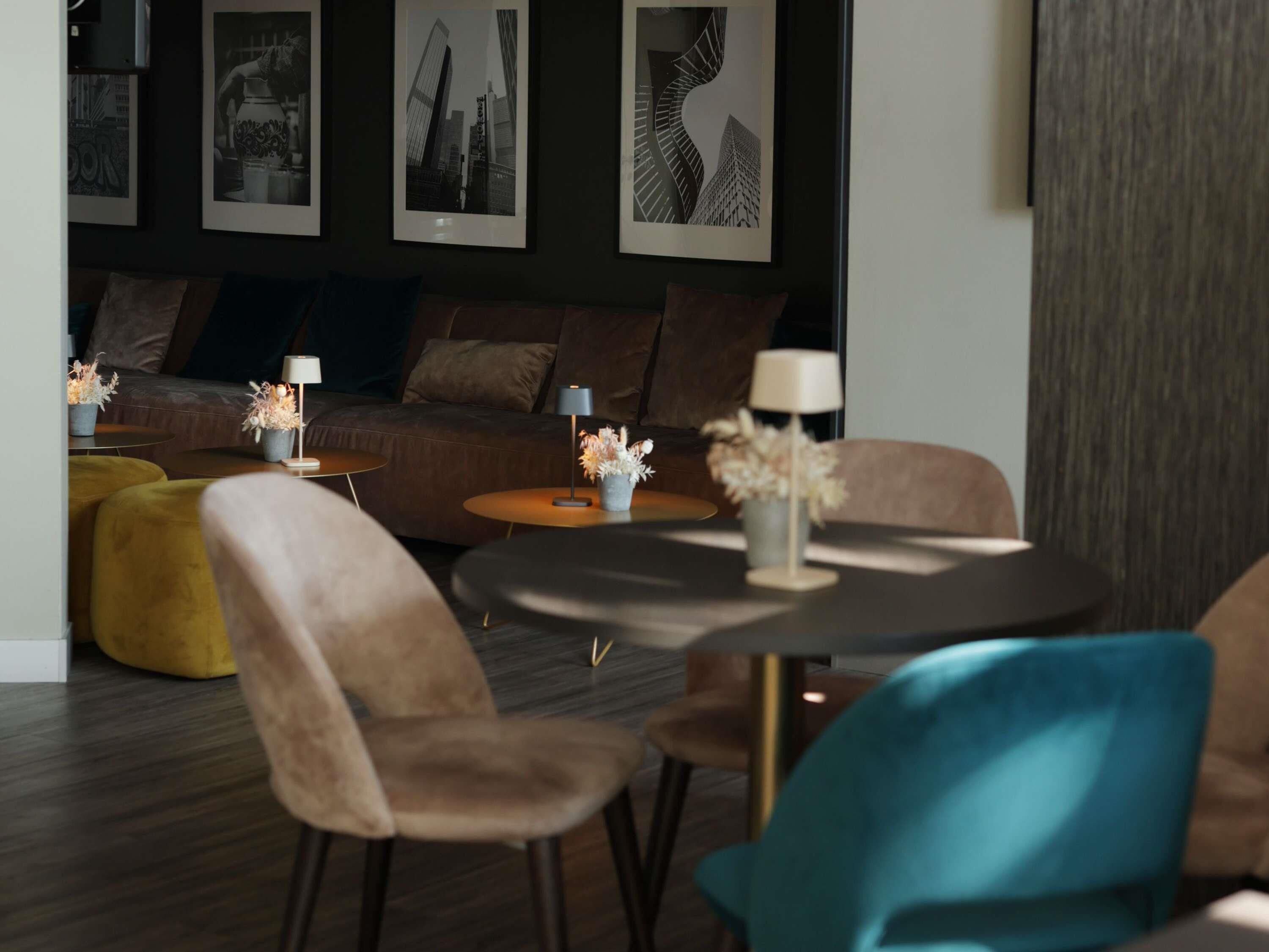 Ein stilvoller Lounge-Bereich mit einer Couch, runden Tischen und Sesseln.