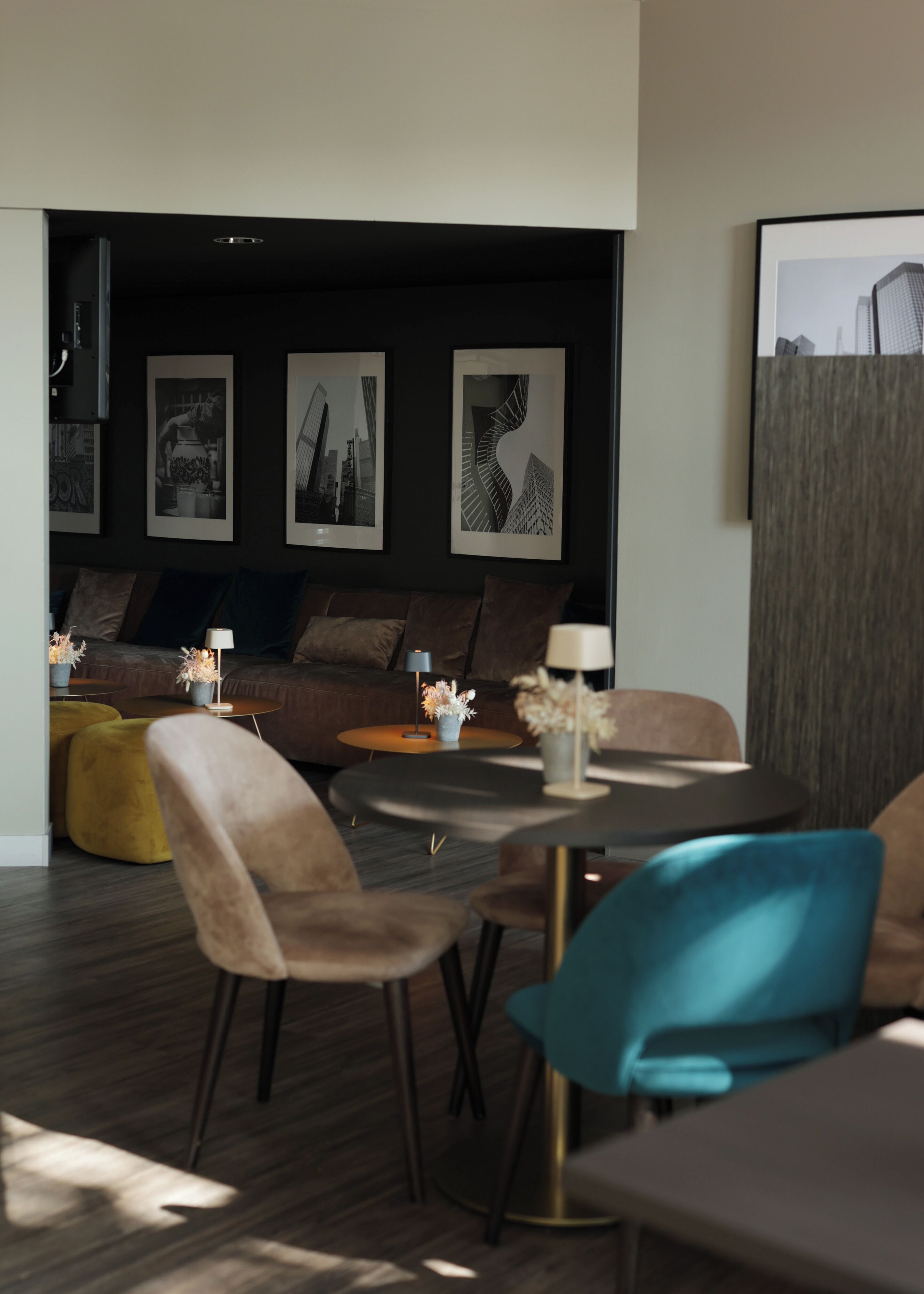A modern living room with a sofa, coffee table, and chairs. There are framed pictures on the wall and a large window.