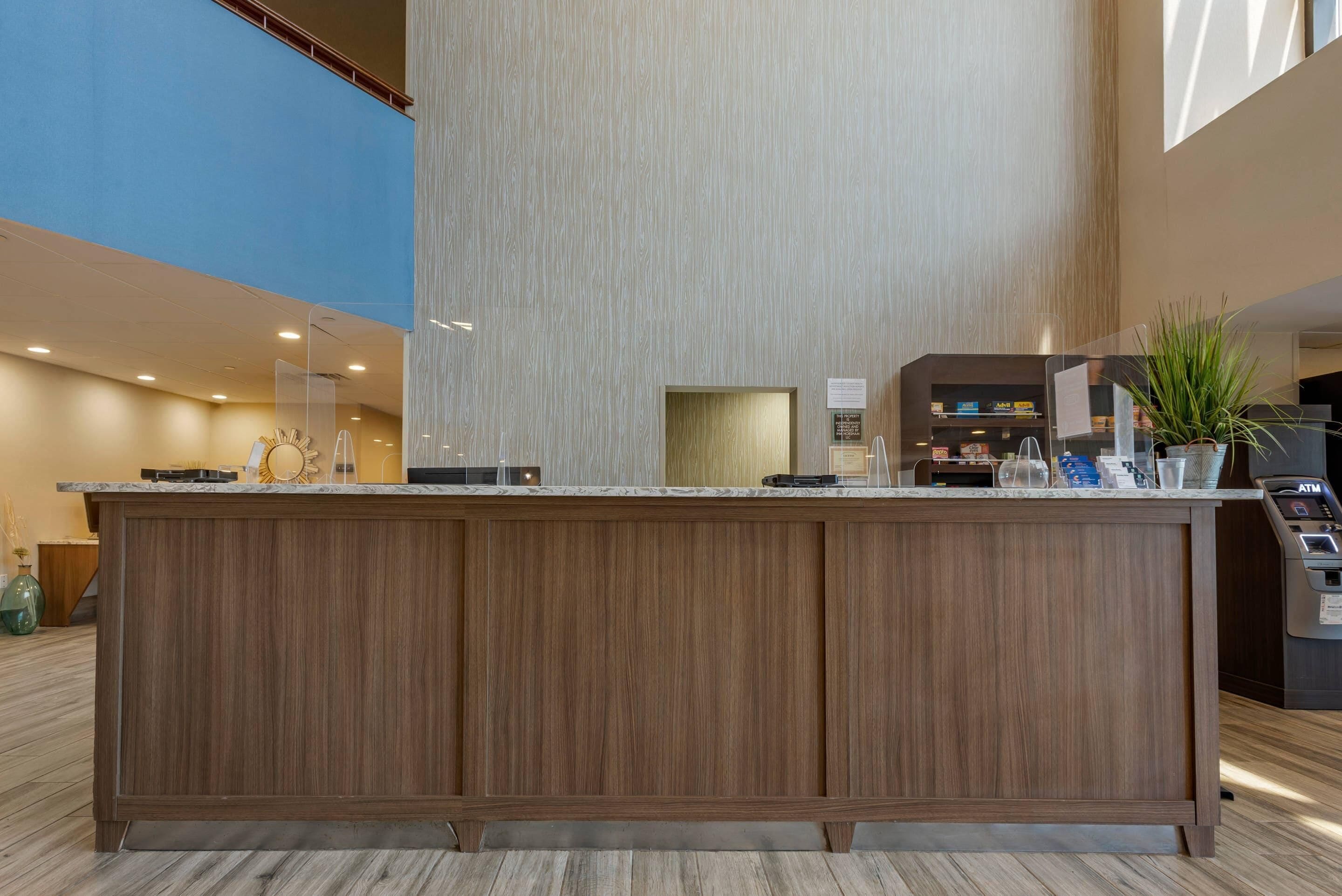 Un'area reception con un bancone in legno, una parete verticale ampia e un soffitto azzurro.