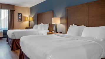 A hotel room with two beds, a nightstand with a lamp, and a framed picture on the wall.