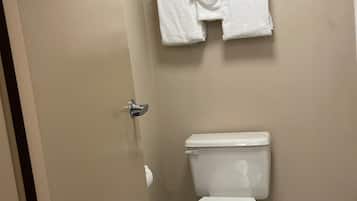 Un baño con inodoro, toallero con dos toallas y dispensador de papel higiénico.