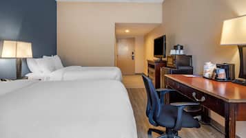 A hotel room with two beds, a desk with a computer, a TV, and a coffee machine.