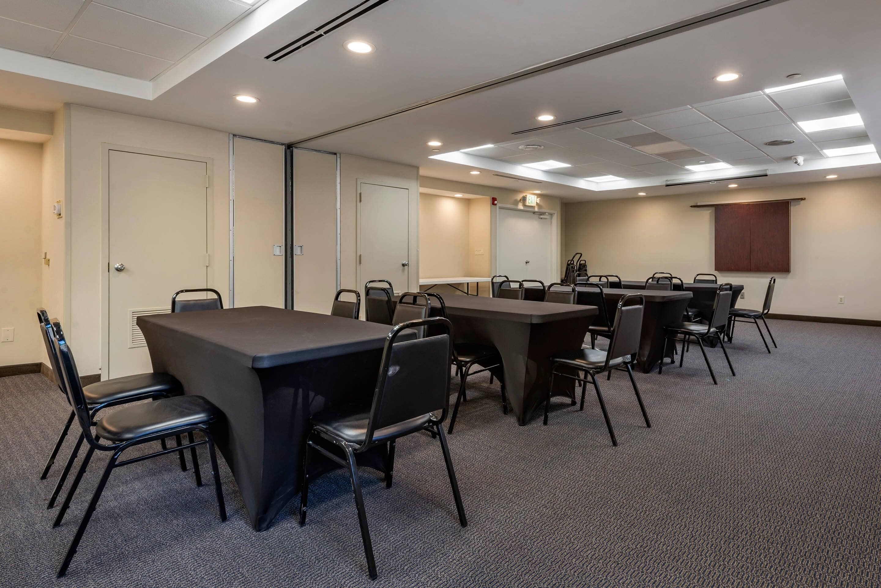 A conference room with a large table, multiple chairs, and a projector screen.