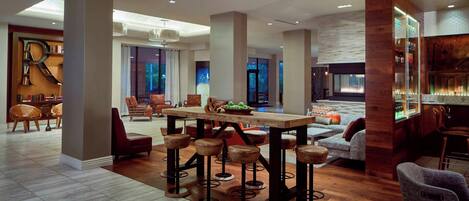 A spacious, modern interior with a central dining area, bar stools, and a bar.