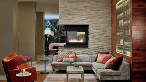 A modern living room with a stone fireplace, a grey sofa, and a red armchair. - Renaissance Asheville Downtown Hotel (Asheville)