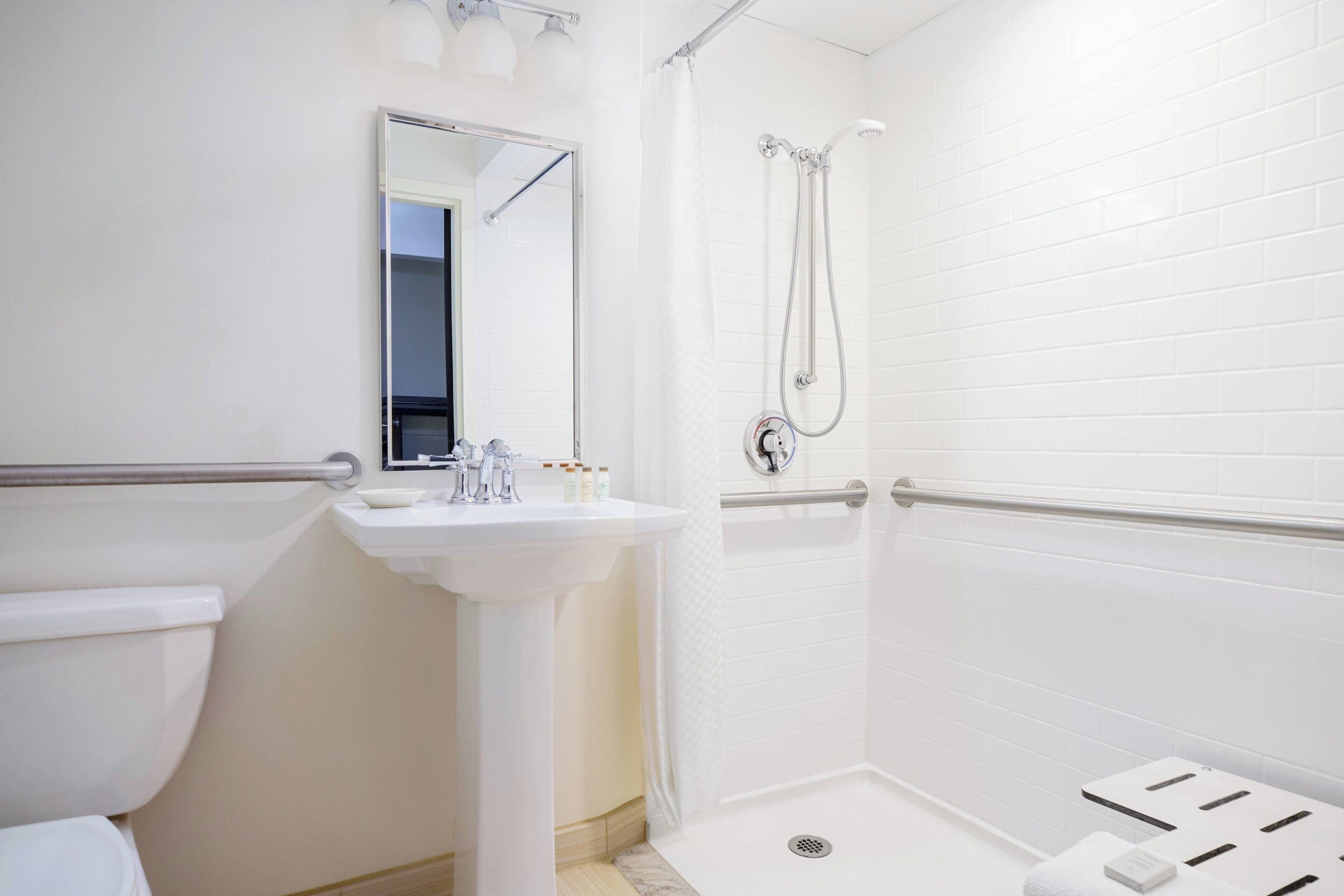 A modern bathroom with a white sink, mirror, and shower.