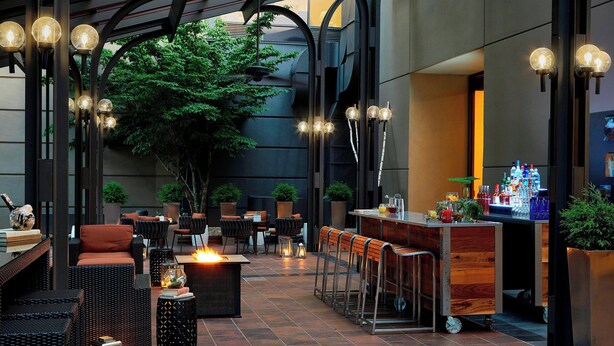 An outdoor seating area with wicker furniture, a bar, and ambient lighting. - Renaissance Asheville Downtown Hotel (Asheville)
