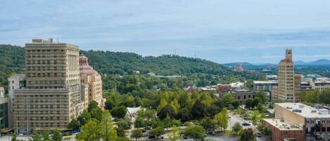 A cityscape with a large parking lot, buildings, and a hilly background.