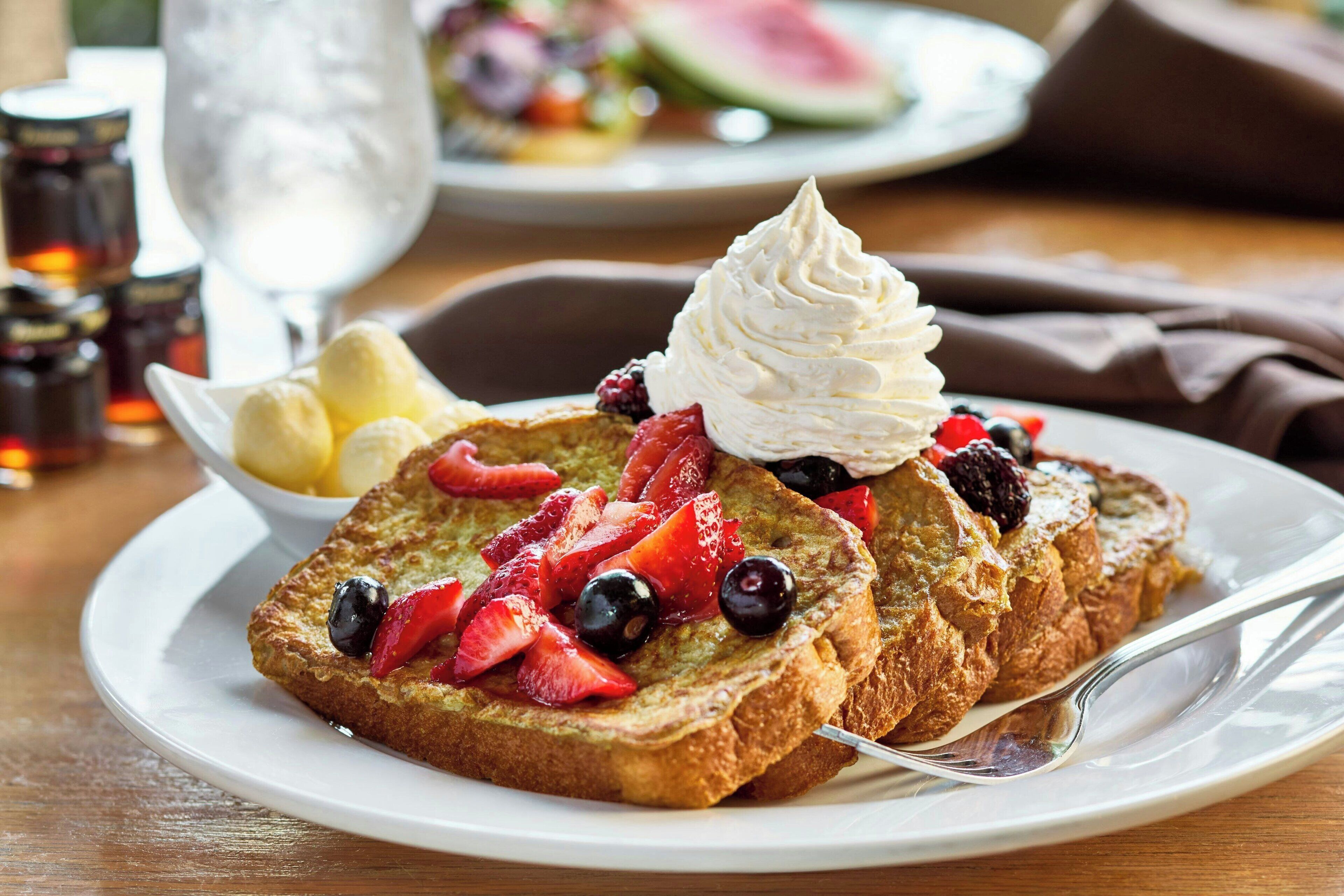A plate of French toast with whipped cream and berries.