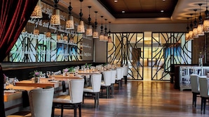 A restaurant with long tables, white chairs, and hanging pendant lights. - Renaissance Asheville Downtown Hotel (Asheville)