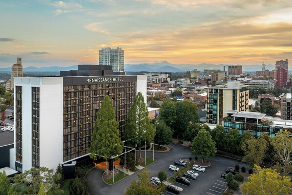 A modern hotel with a prominent sign, surrounded by urban buildings and a parking lot. - Renaissance Asheville Downtown Hotel (Asheville)
