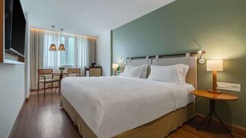 Une chambre d’hôtel avec un grand lit, un bureau, des chaises, une télévision et une lampe.