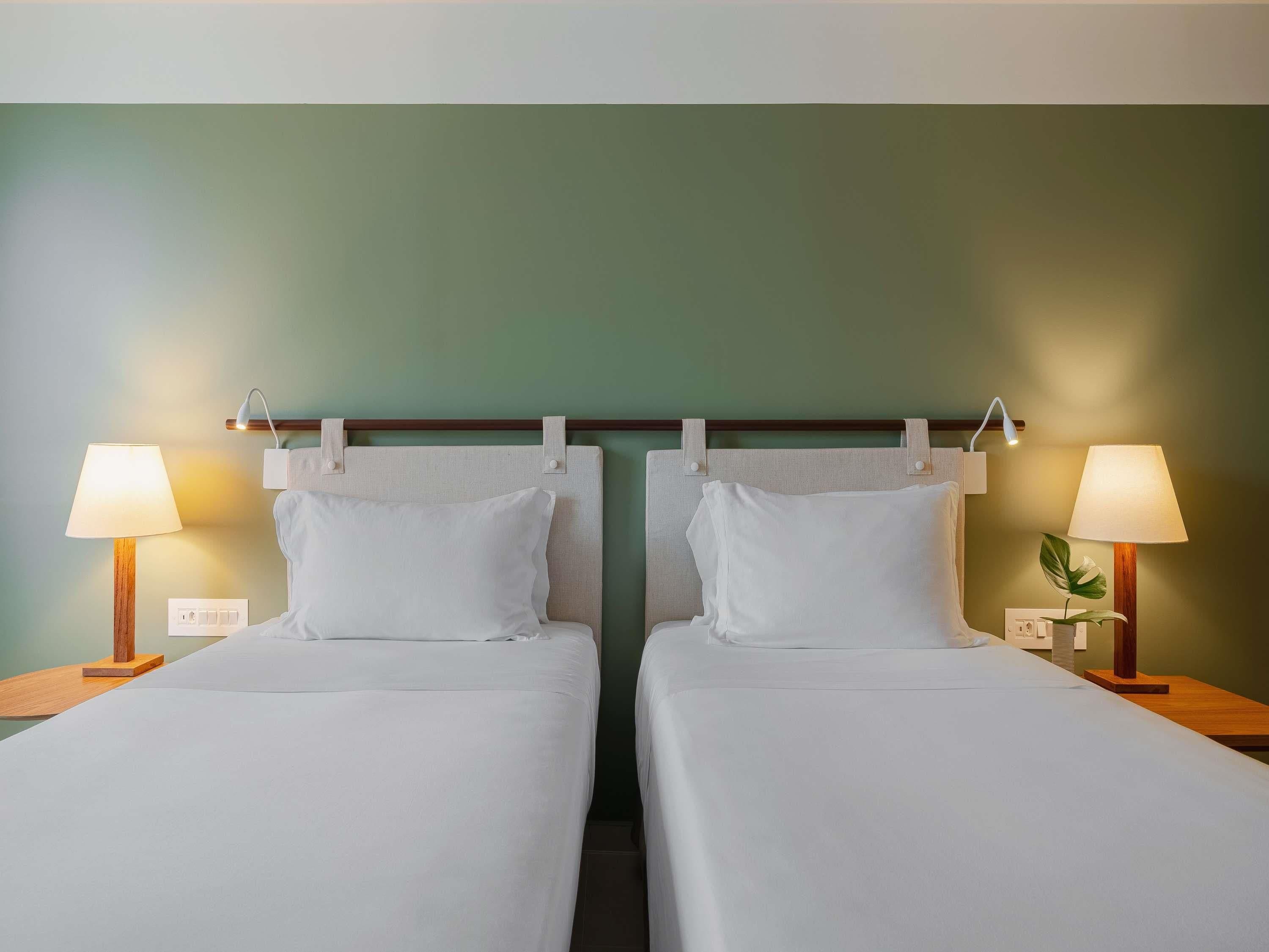 Une chambre d’hôtel avec deux lits simples, chacun étant équipé d’une table de chevet et d’une lampe.