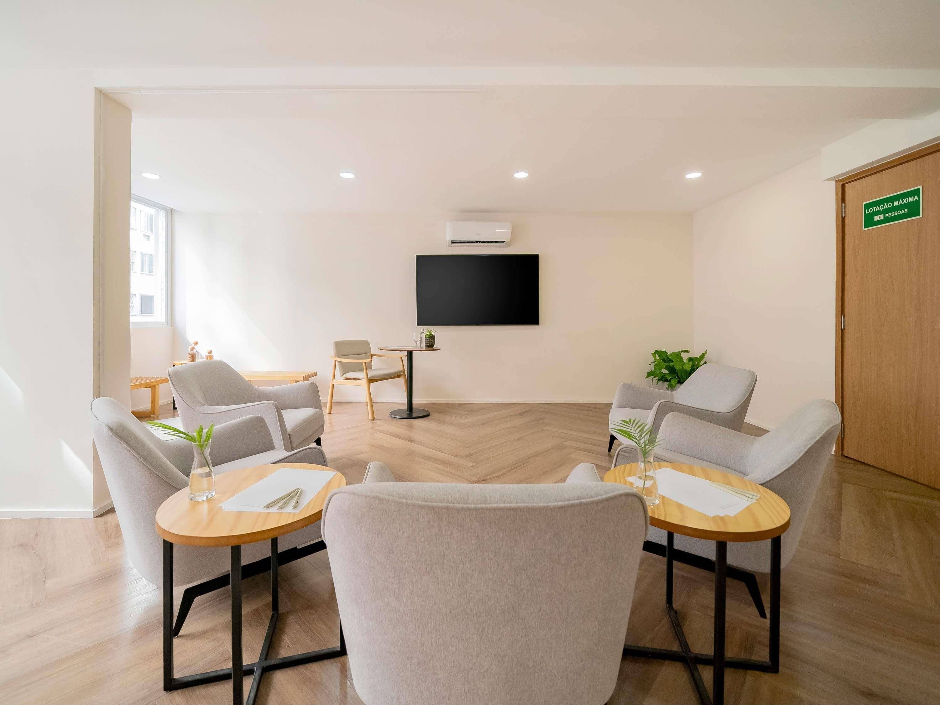 Una habitación moderna con televisión, asientos y una puerta de madera.