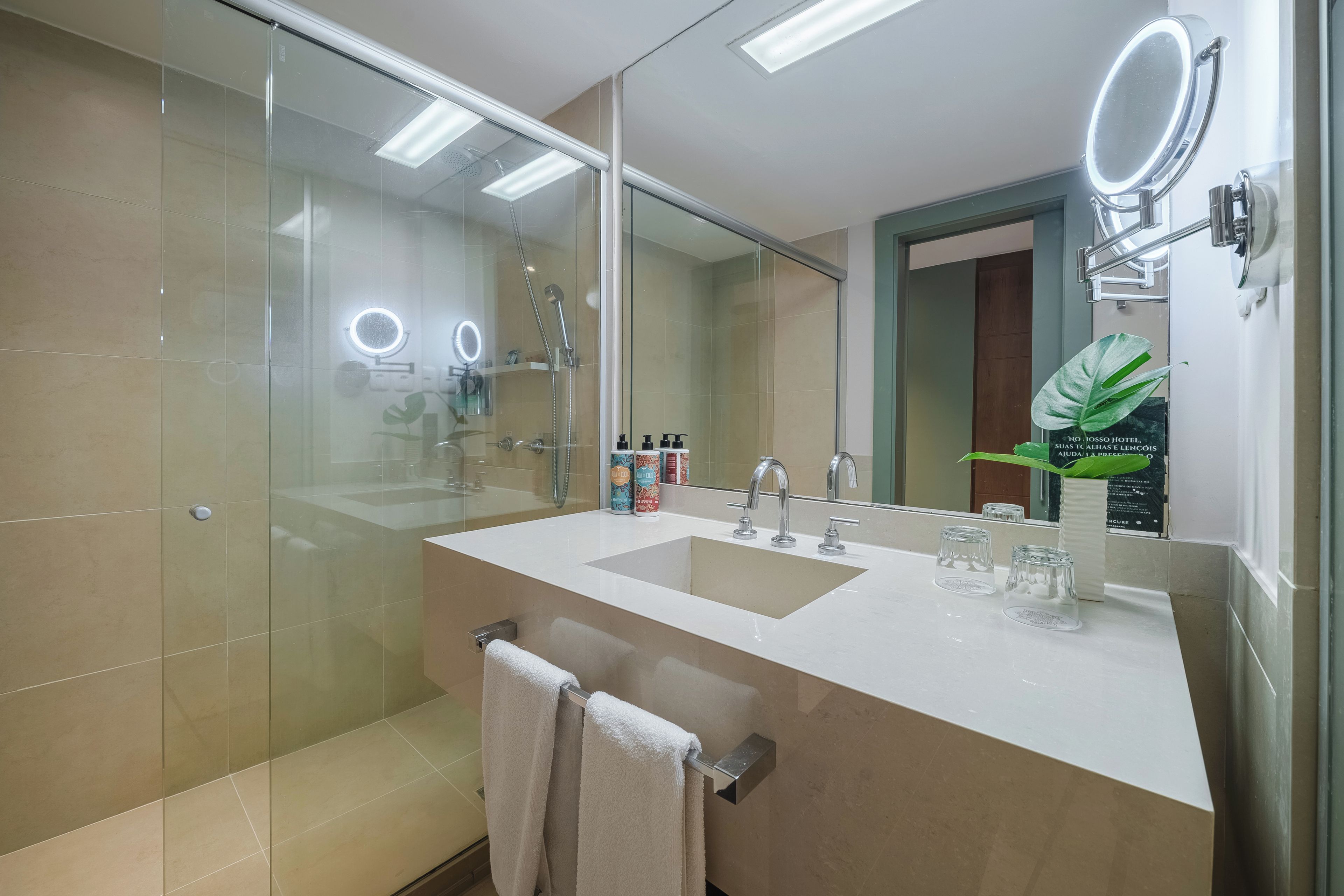 Une salle de bain moderne avec une douche à parois de verre, un meuble-lavabo doté de deux vasques et un grand miroir.