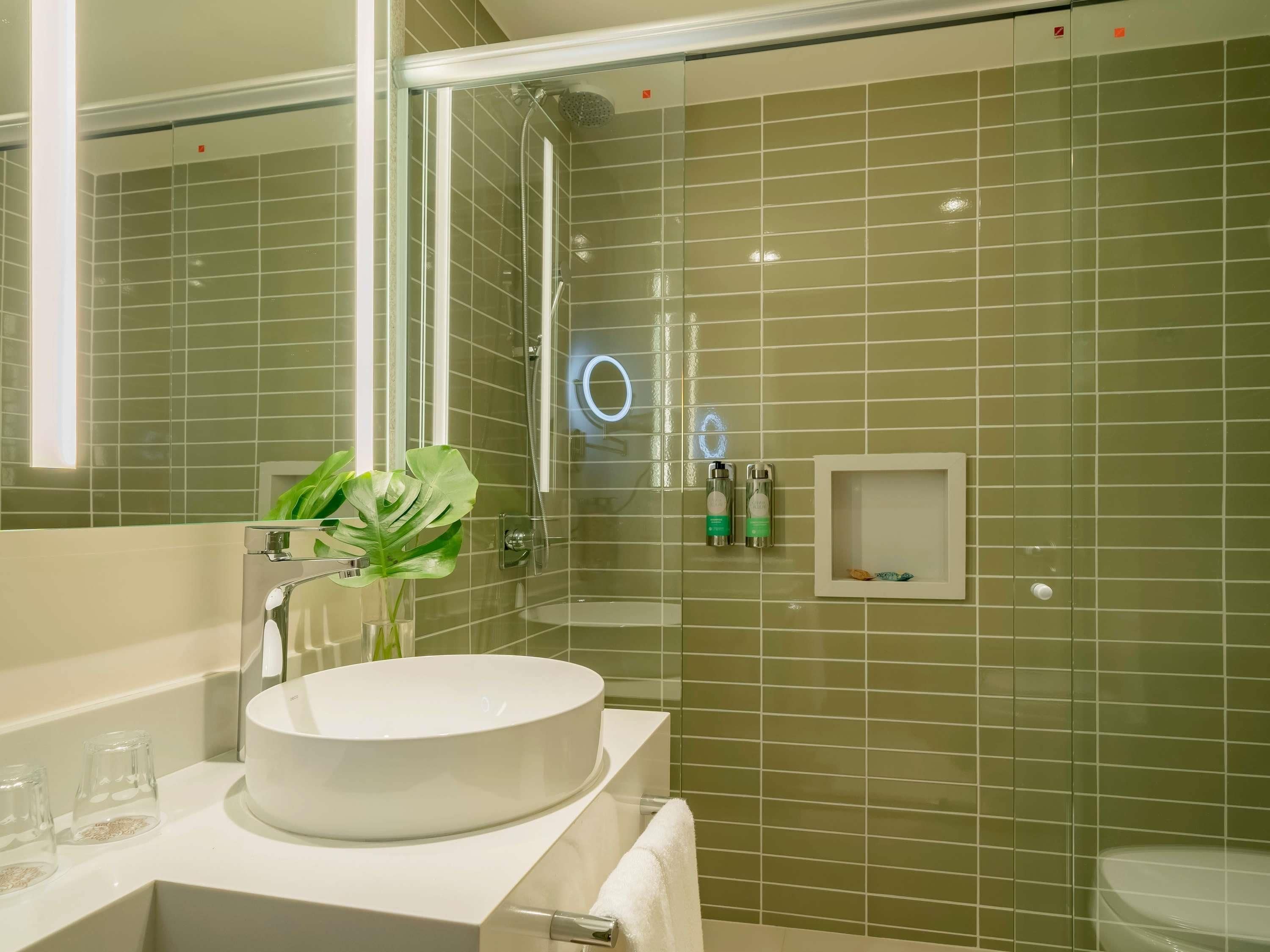 Un baño con un lavabo redondo, una cabina de ducha de cristal y un espejo.