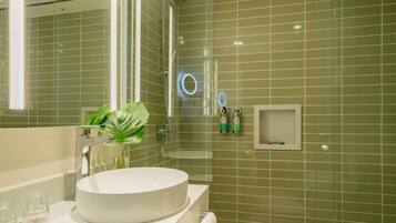 Un baño con un lavabo redondo, una cabina de ducha de cristal y un espejo.