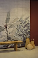 A tiled wall with a botanical pattern, a wooden bench, and two woven baskets.