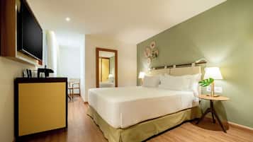 A hotel room with a bed, bedside table, lamp, and a television on a stand.