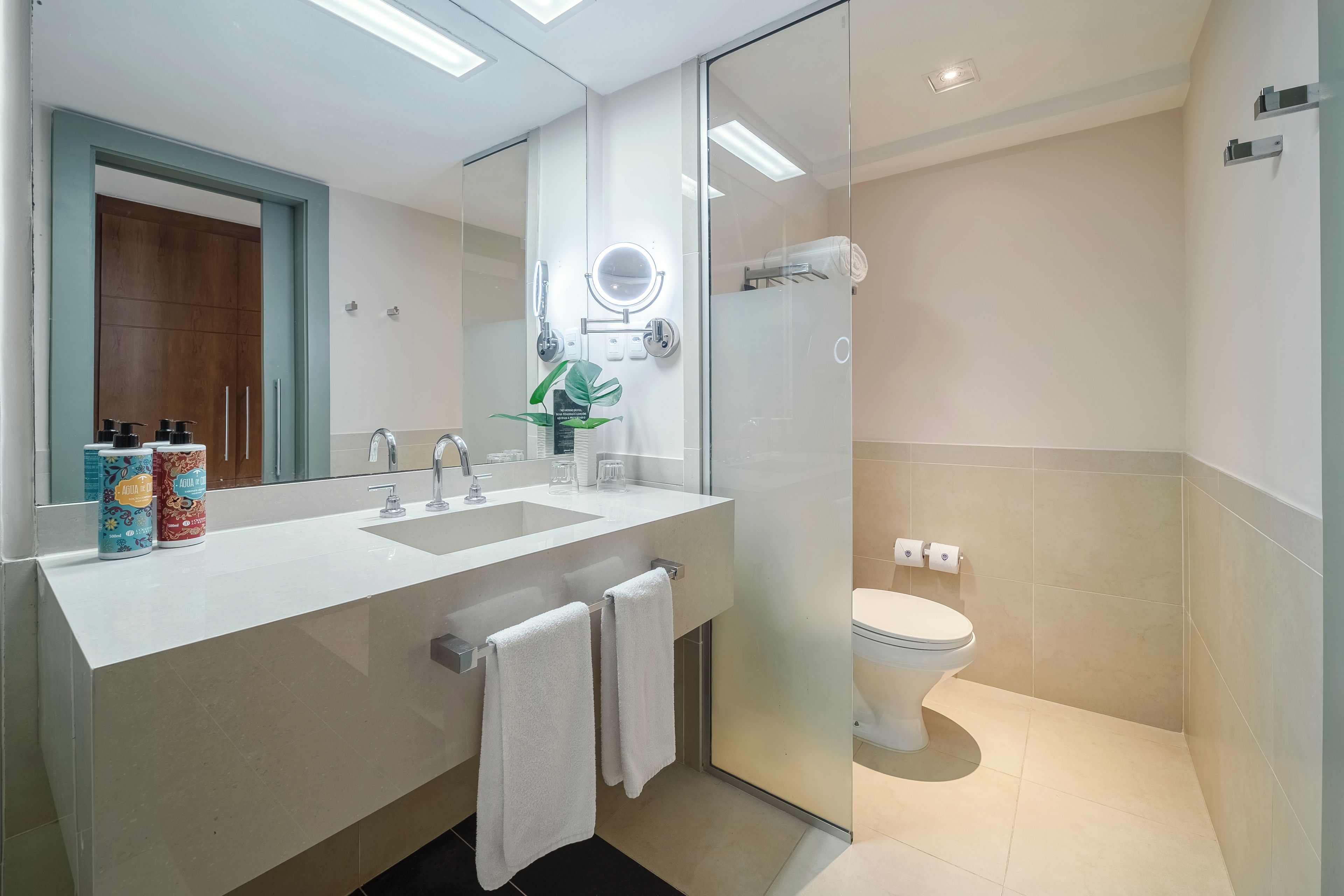 Een moderne badkamer met een douchecabine van glas, een wit wastafelmeubel met twee kraan en een toilet.