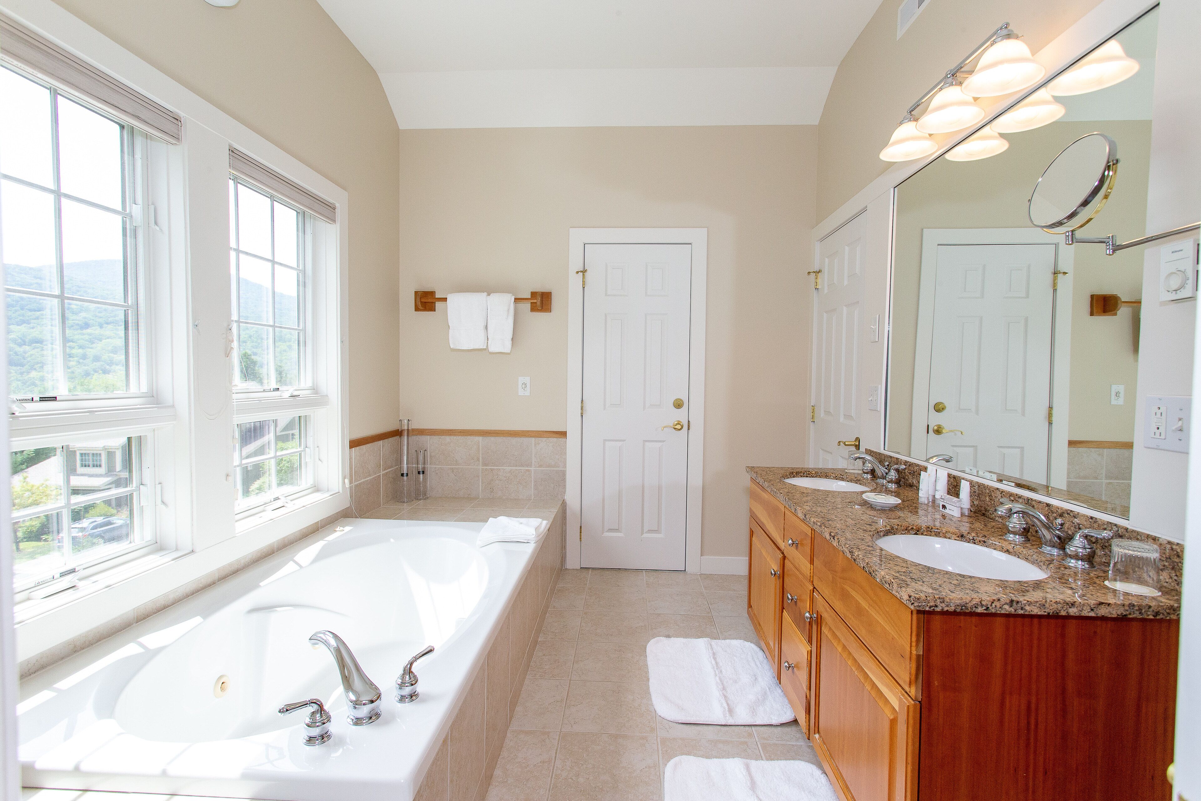 A bathroom with a large bathtub, two sinks, and a vanity with a mirror.