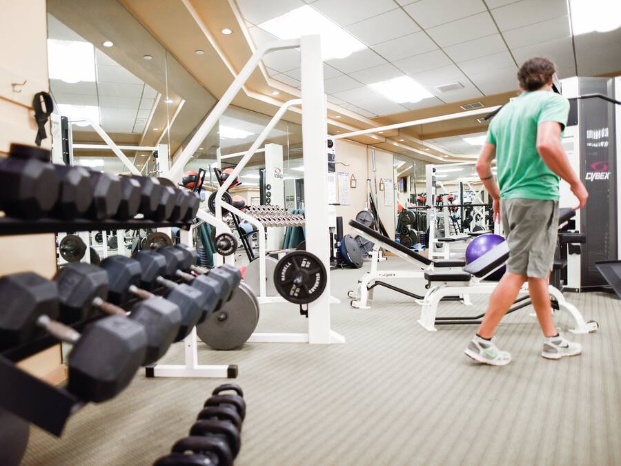 Un gimnasio con equipo de ejercicio, incluyendo pesas y máquinas de musculación.