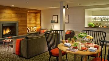 A cozy living room with a fireplace, comfortable seating, and a dining area with a variety of food and drinks.