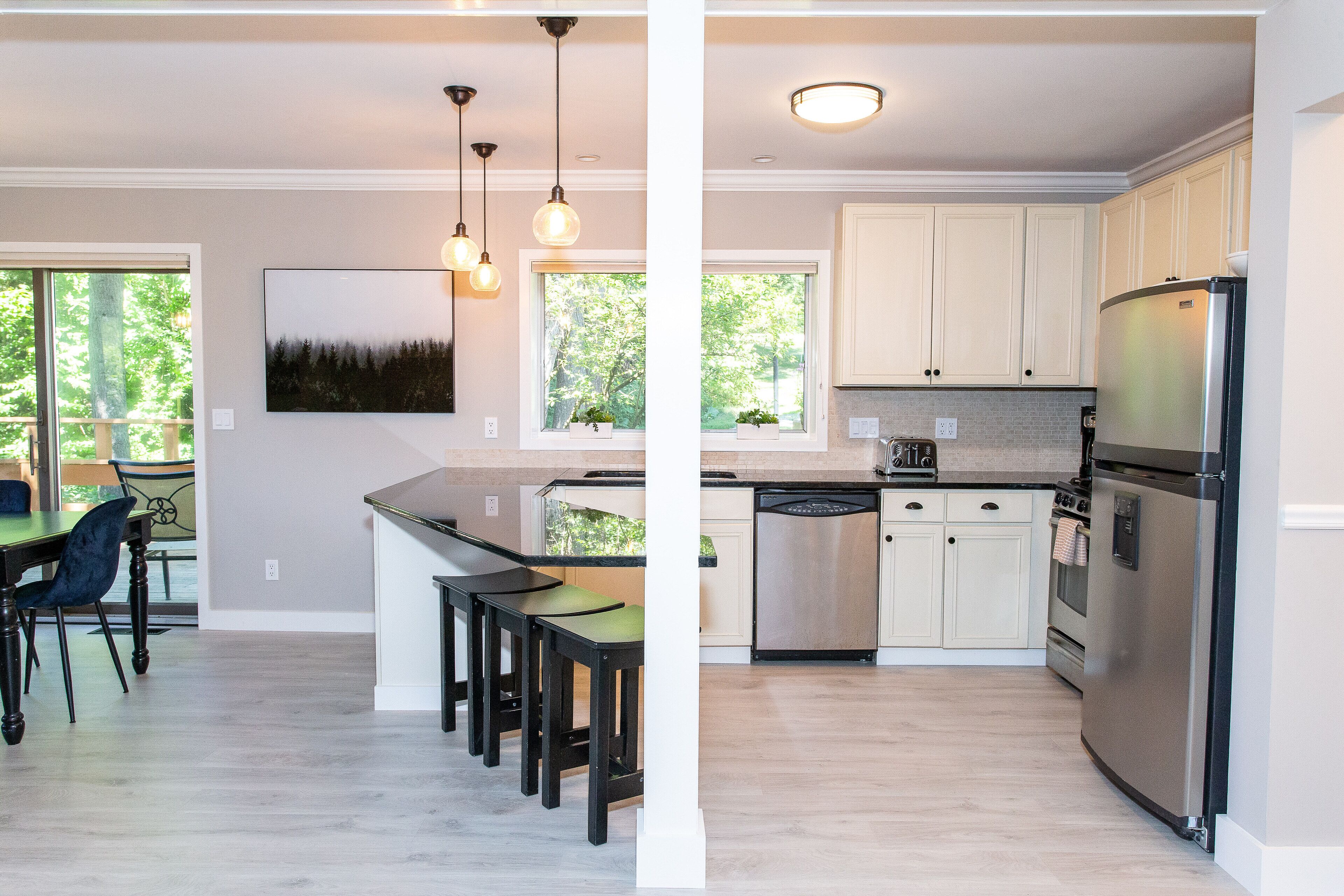 A modern kitchen with light wood flooring, stainless steel appliances, and a dining area with a table and chairs.