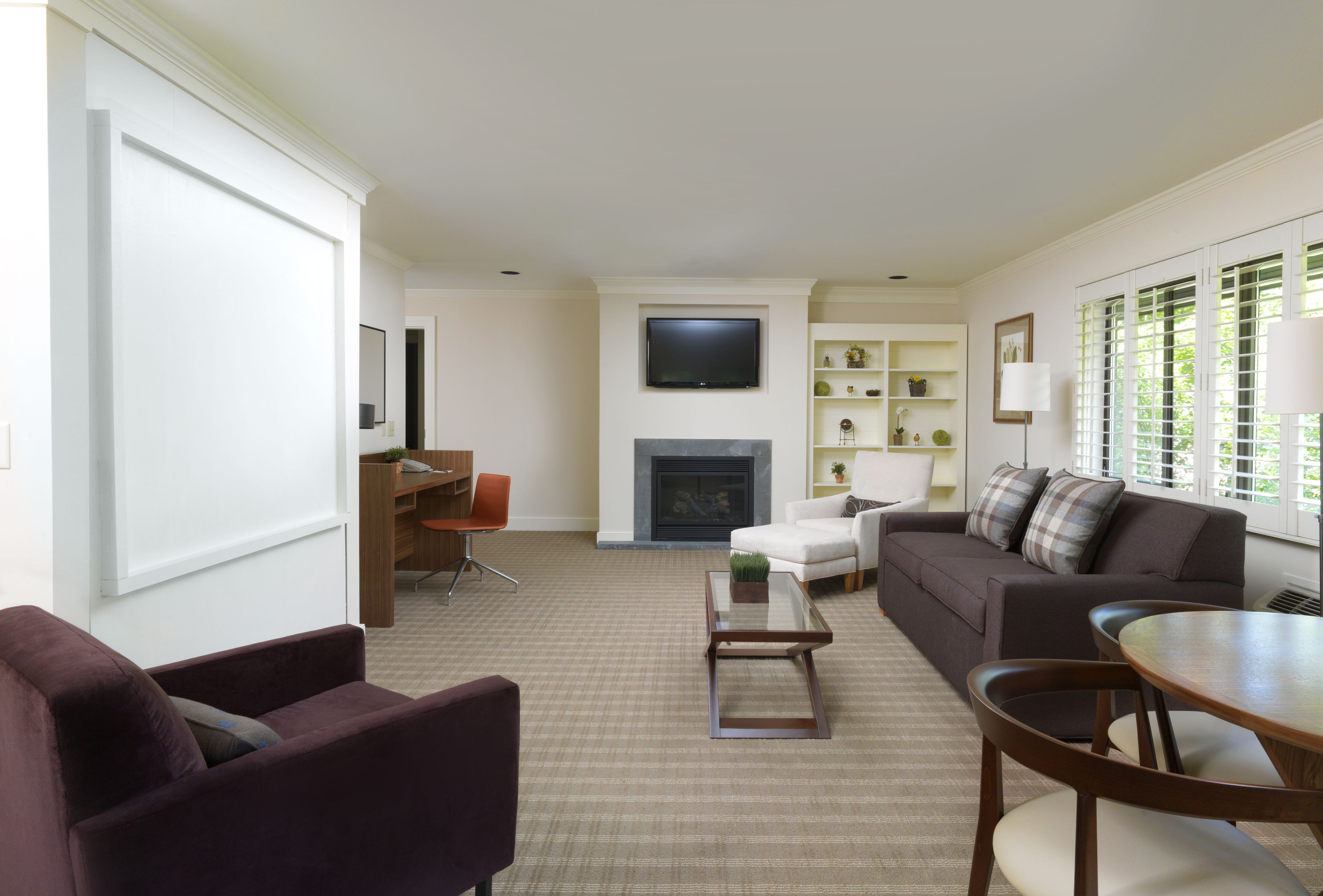 A living room with a fireplace, a television, and a seating area with a couch and chairs.